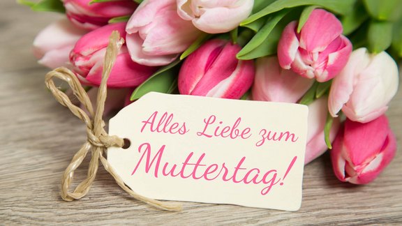 Muttertagsgrüße – Feiern Sie den Early Muttertag im Hotel Post Hönig! Ein Strauß rosa Tulpen mit einem Geschenkanhänger, auf dem 'Alles Liebe zum Muttertag!' steht.